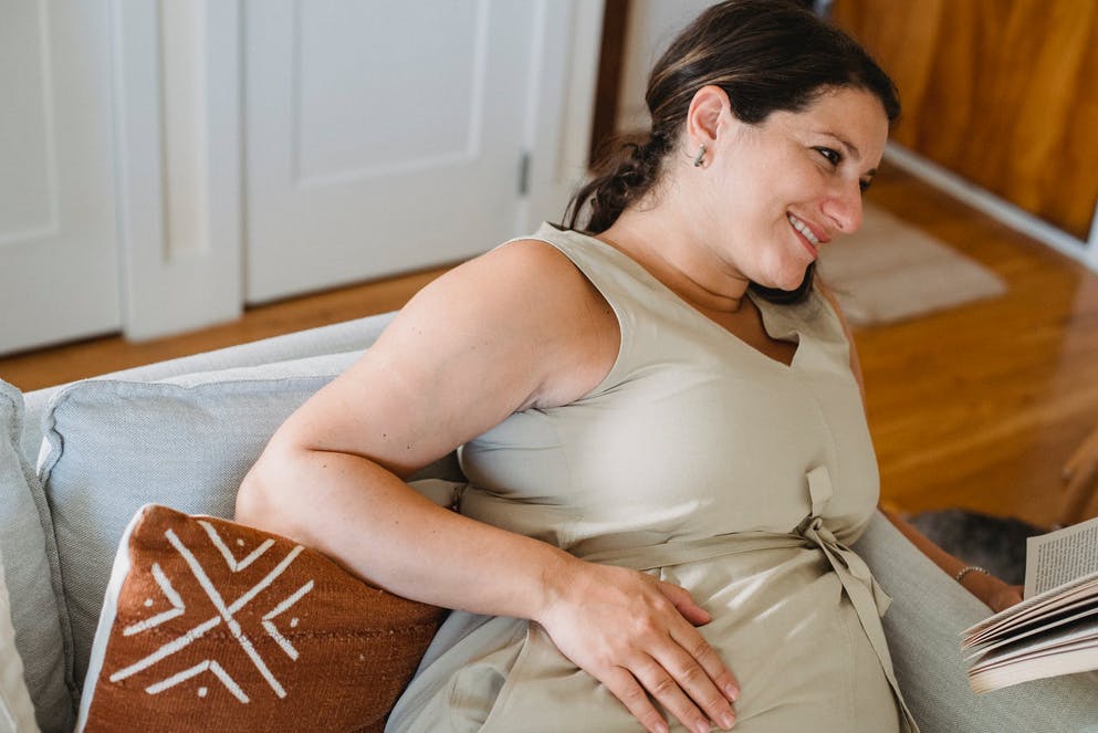 woman in beige shirt holding her pregnant stomach