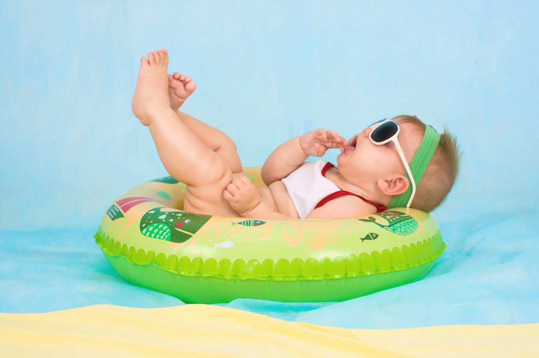 baby wearing sunglasses relaxing on a pool float
