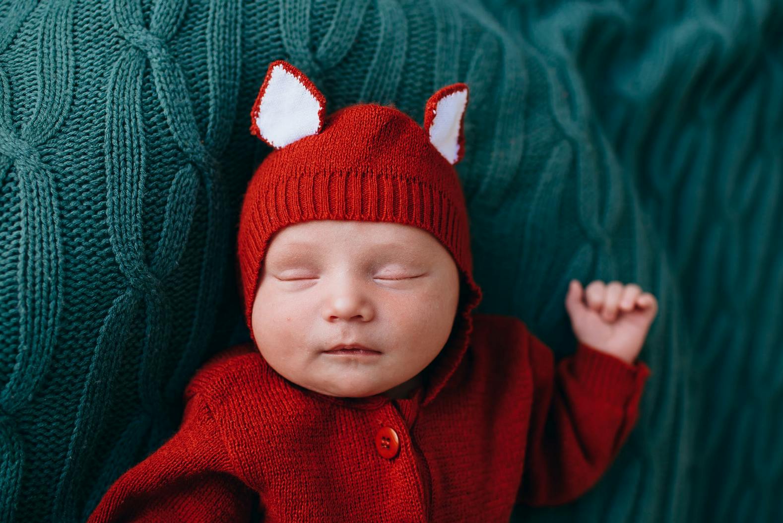 newborn baby in red pajamas sleeping