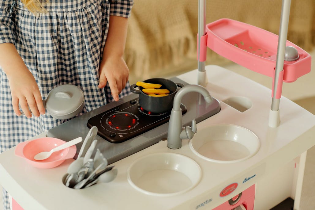 toddler in front of play kitchen