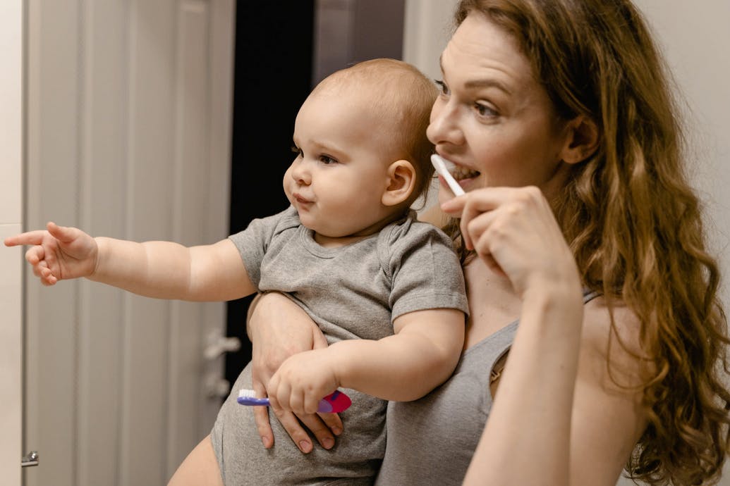 mom and baby looking in a mirror brushing teeth