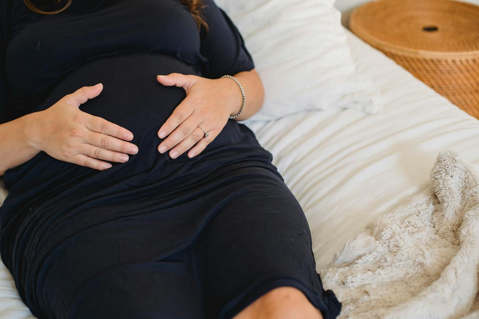 woman in black dress holding her pregnant stomach