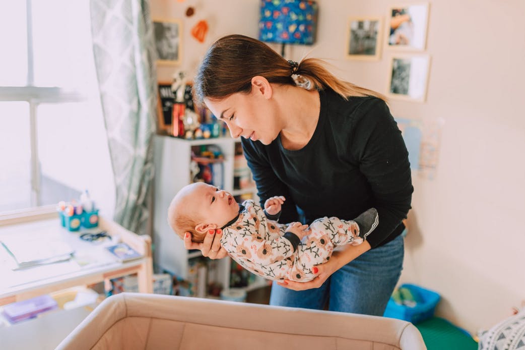 mom laying newborn baby into bassinet