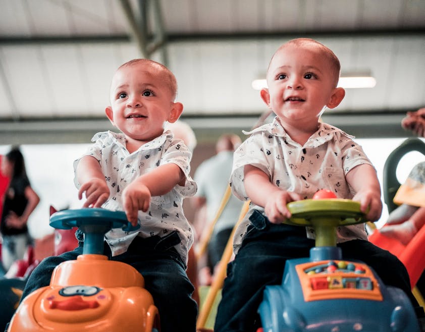 baby twin boys riding cars together