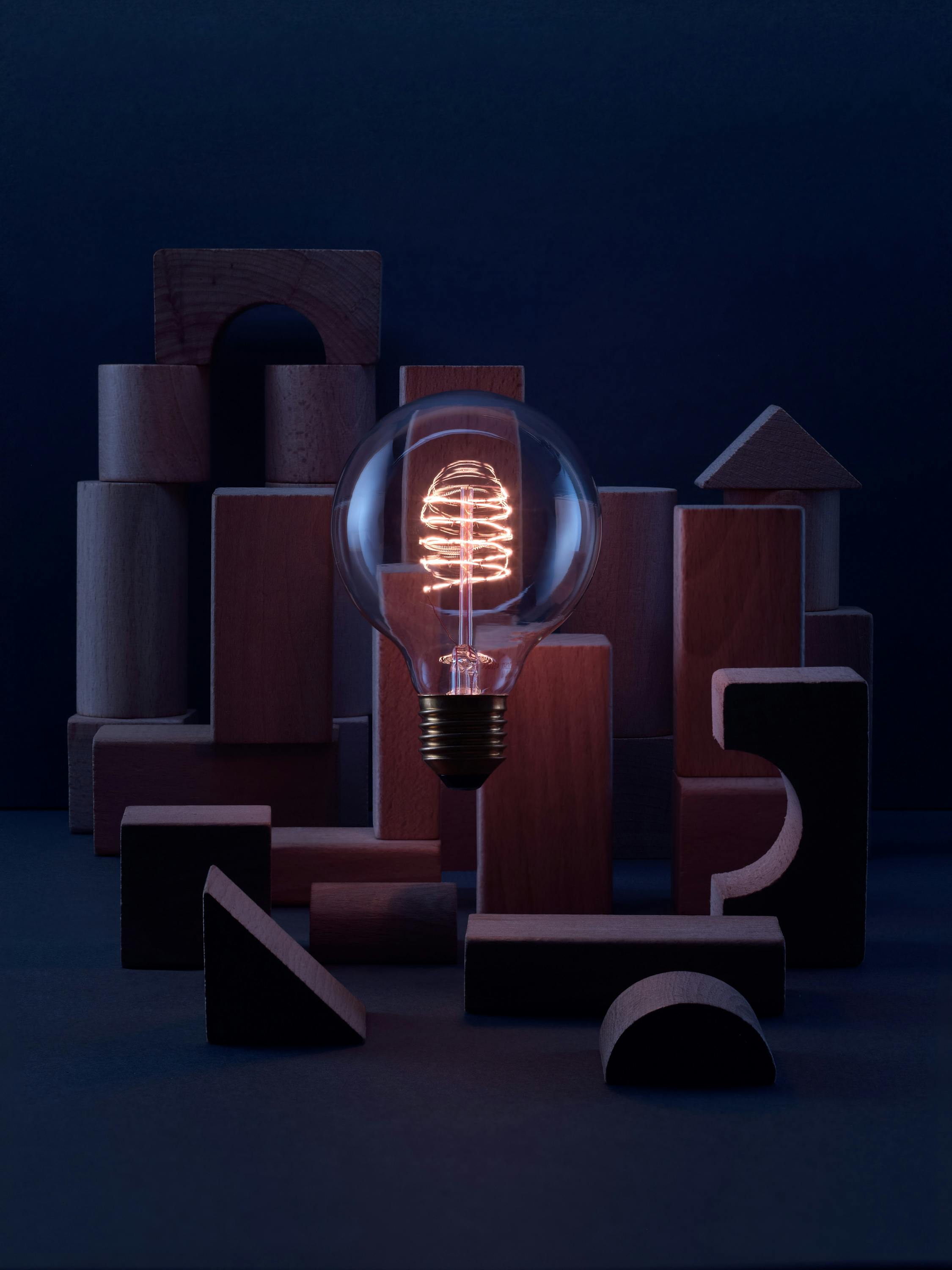 Light bulb with wooden building blocks in a dark blue set