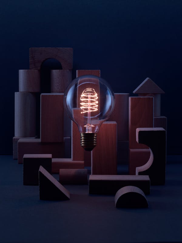 Light bulb with wooden building blocks in a dark blue set