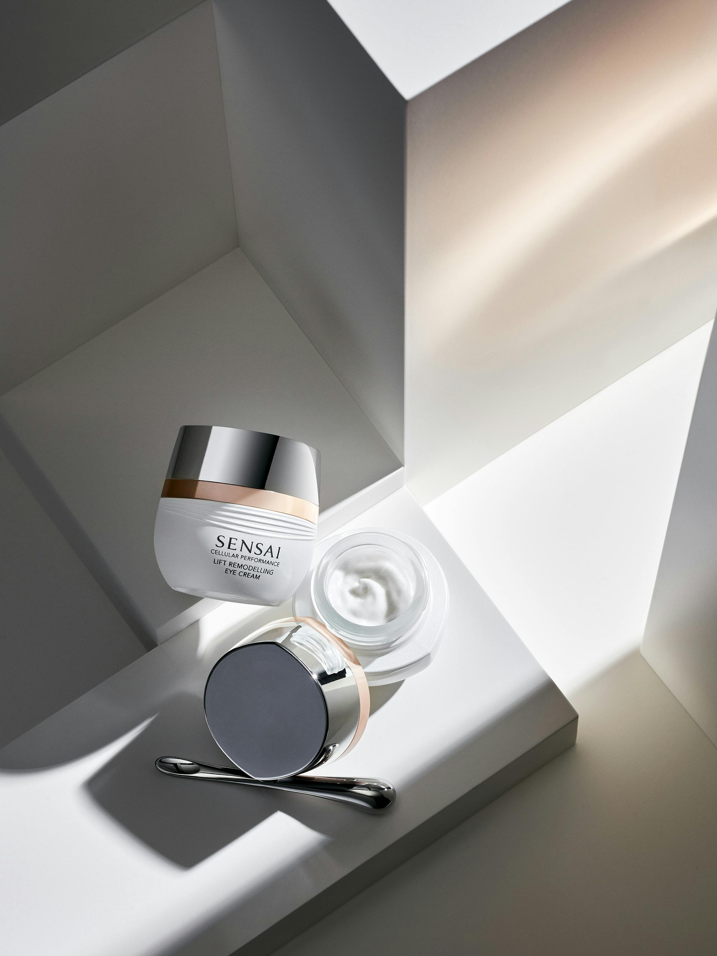 A white box containing beauty cream on white pedestals, with golden light shining in from the right-hand side.