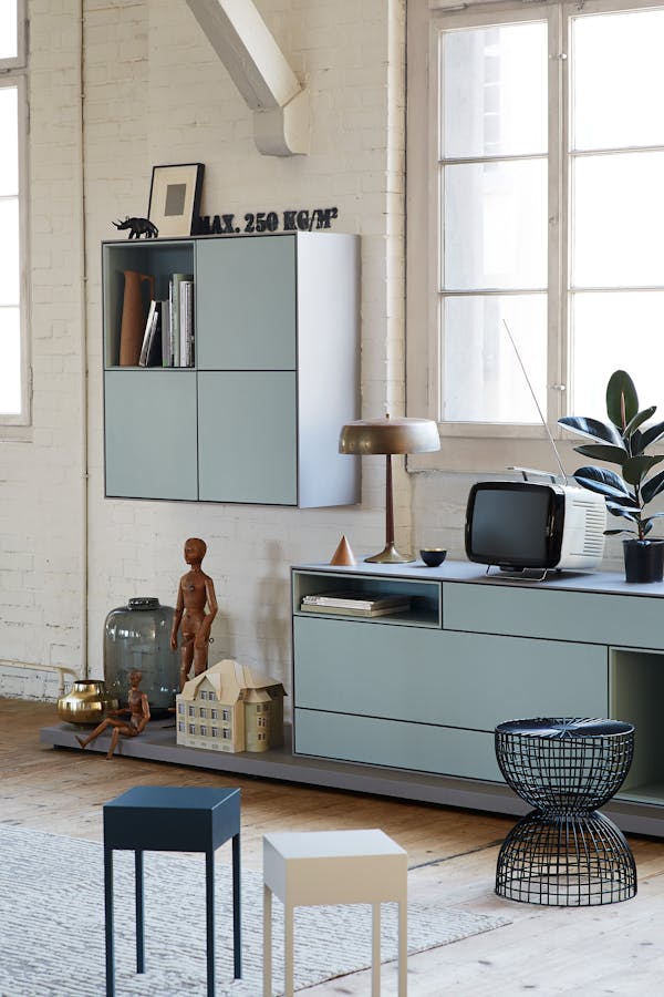 A light blue sideboard in a factory loft on a wooden plank floor.