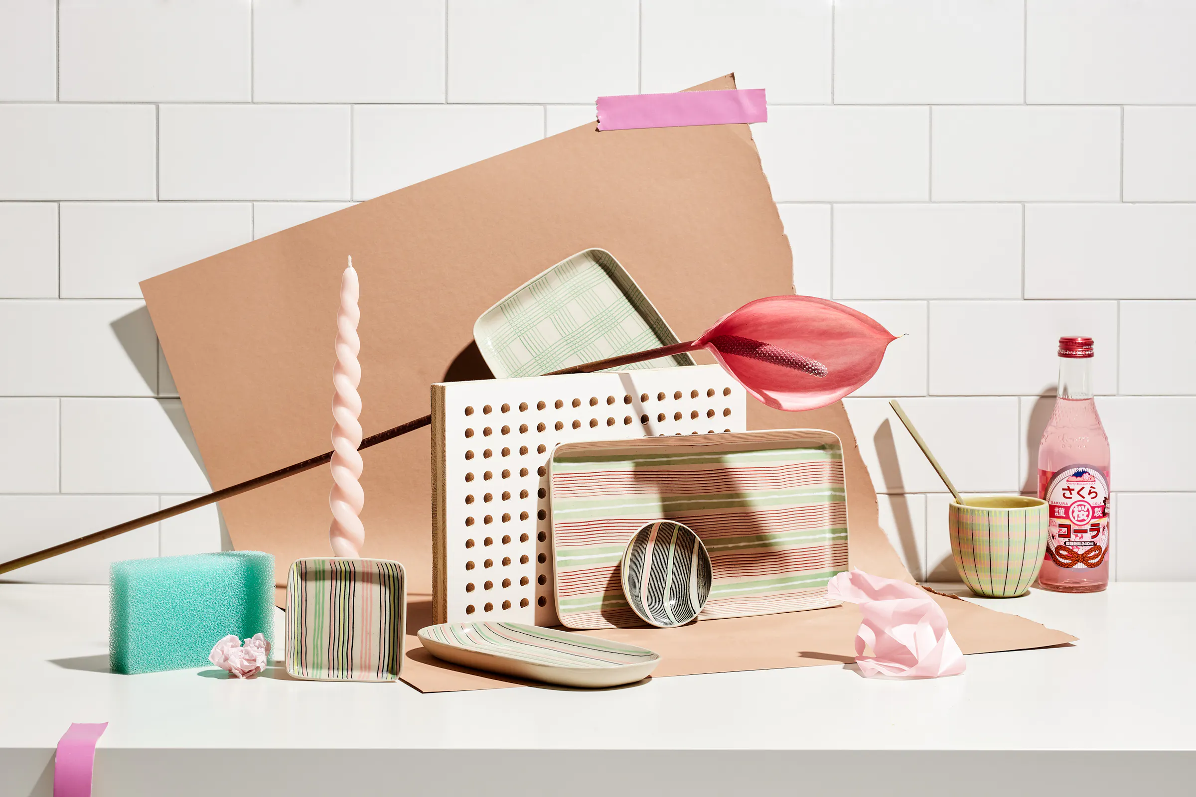 Various ceramic objects by Simone Fennel in front of a wall with tiles and a nude colored paper