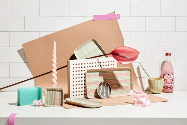 Various ceramic objects by Simone Fennel in front of a wall with tiles and a nude colored paper