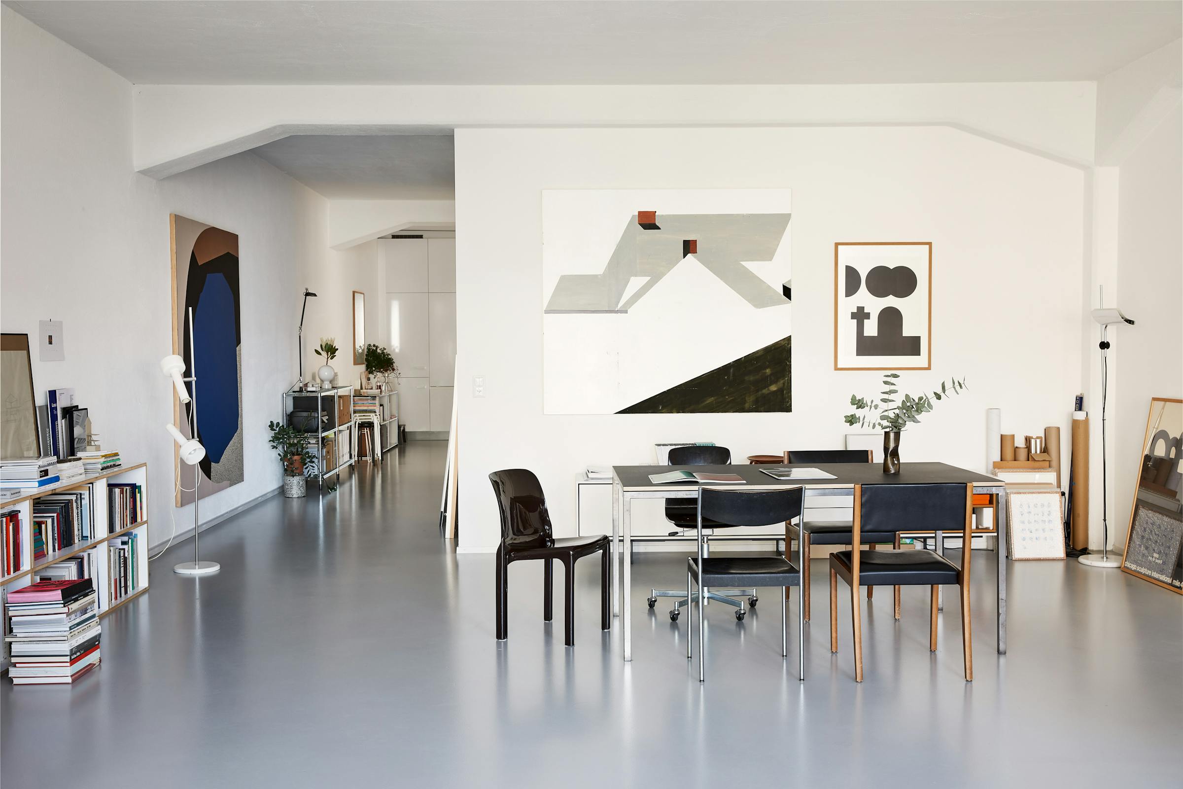 Dining table with various chairs in a loft with graphic pictures on the wall