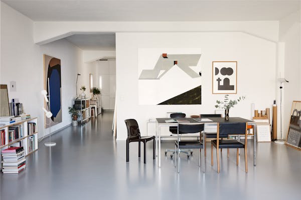 Dining table with various chairs in a loft with graphic pictures on the wall