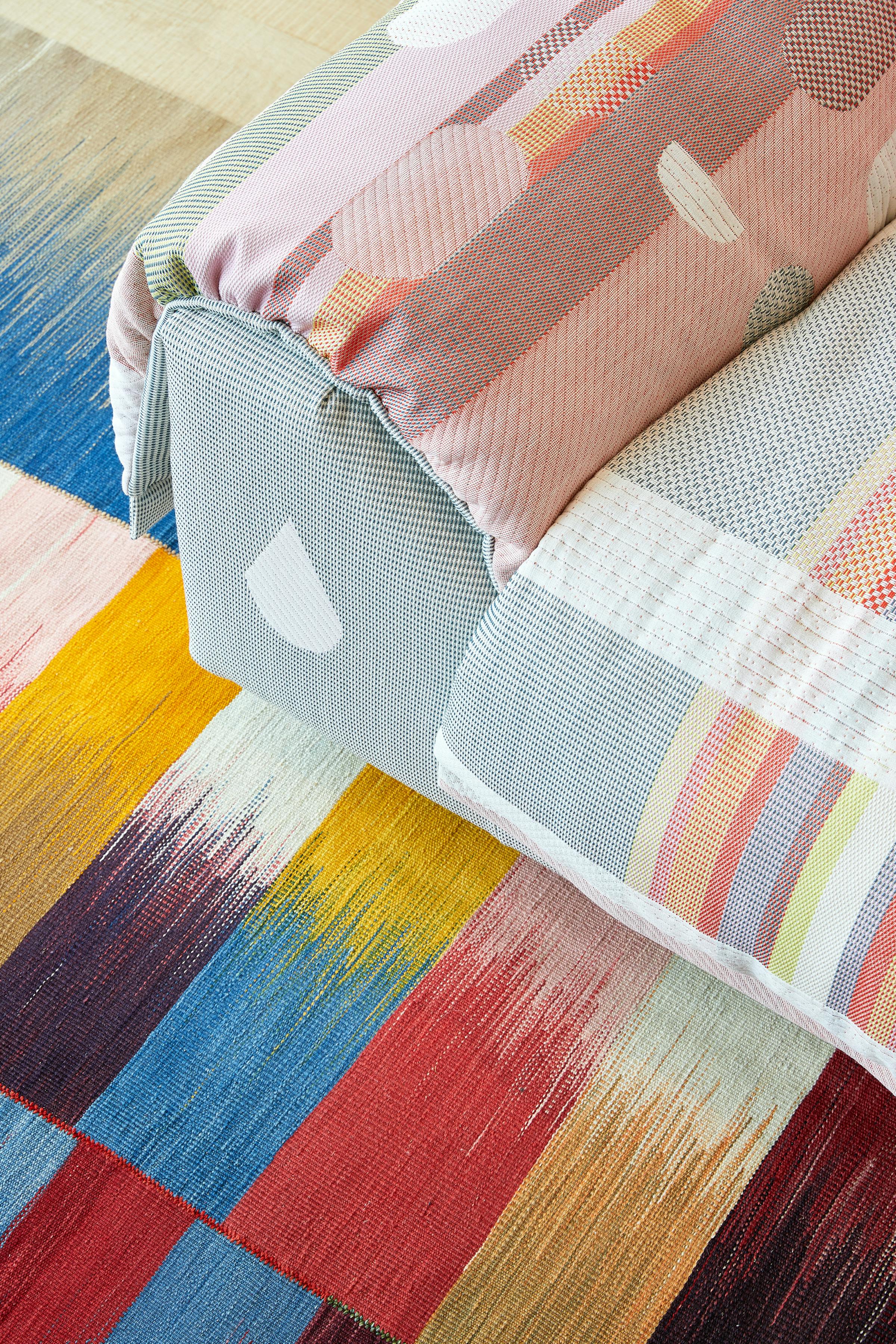 Close-up of a sofa with a coloured rug underneath