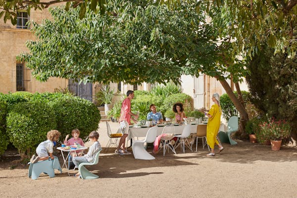 Long, festively laid dining table under a tree with a cheerful group of people
