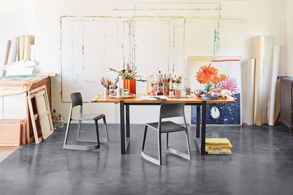 Table in an artist's studio with two TipTon chairs and several pencil holders on top
