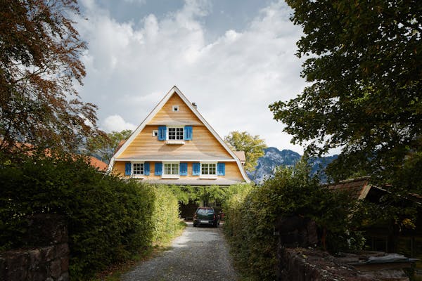 Front view of a 19th-century house with a pitched roof in the mountains