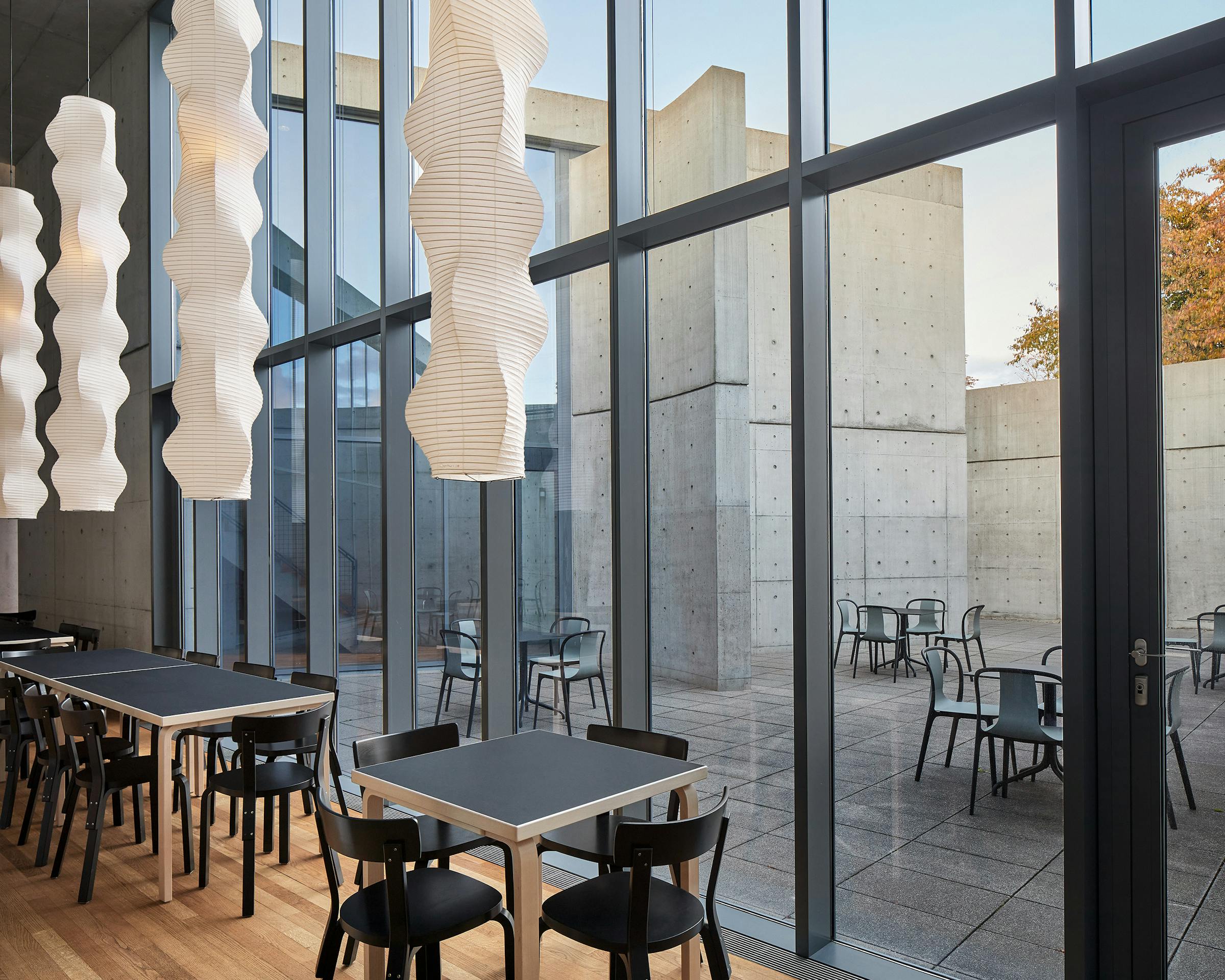 View from the Tadao Ando Pavilion at the vitra campus in Weil am Rhein  into the inner courtyard, long paper lights by Ismau Noguchi hang from the ceiling