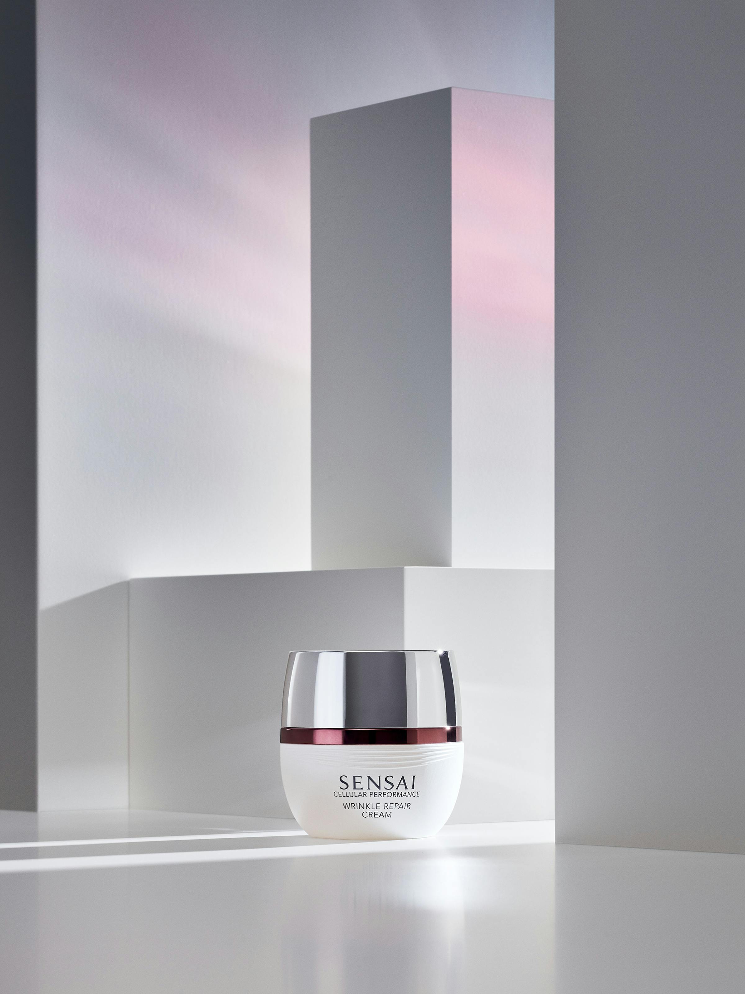 A white box containing beauty cream i a set of white pedestals, with red light shining in from the right-hand side.