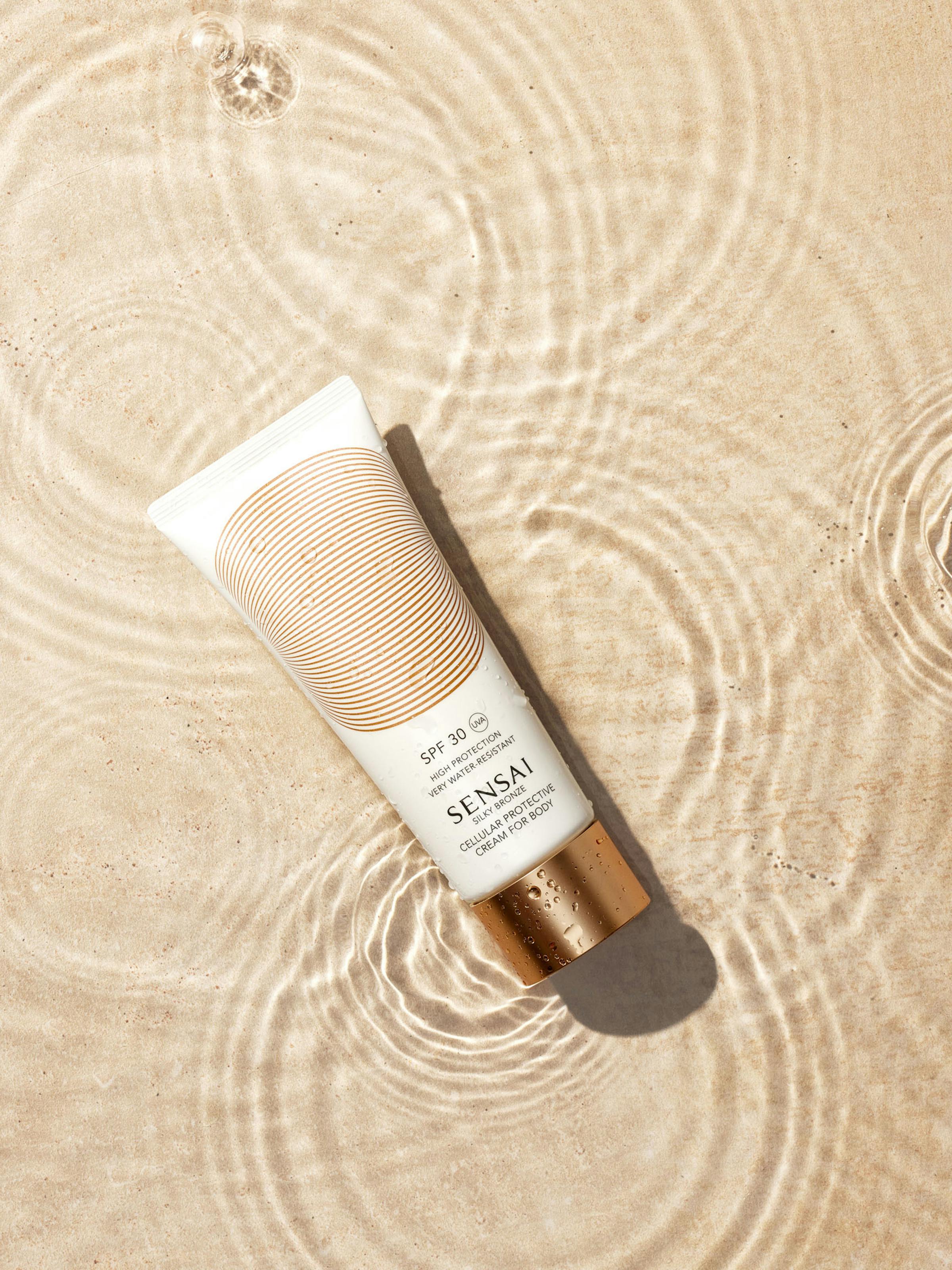 White sun cream tube with golden cap in a water basin with travertine base 