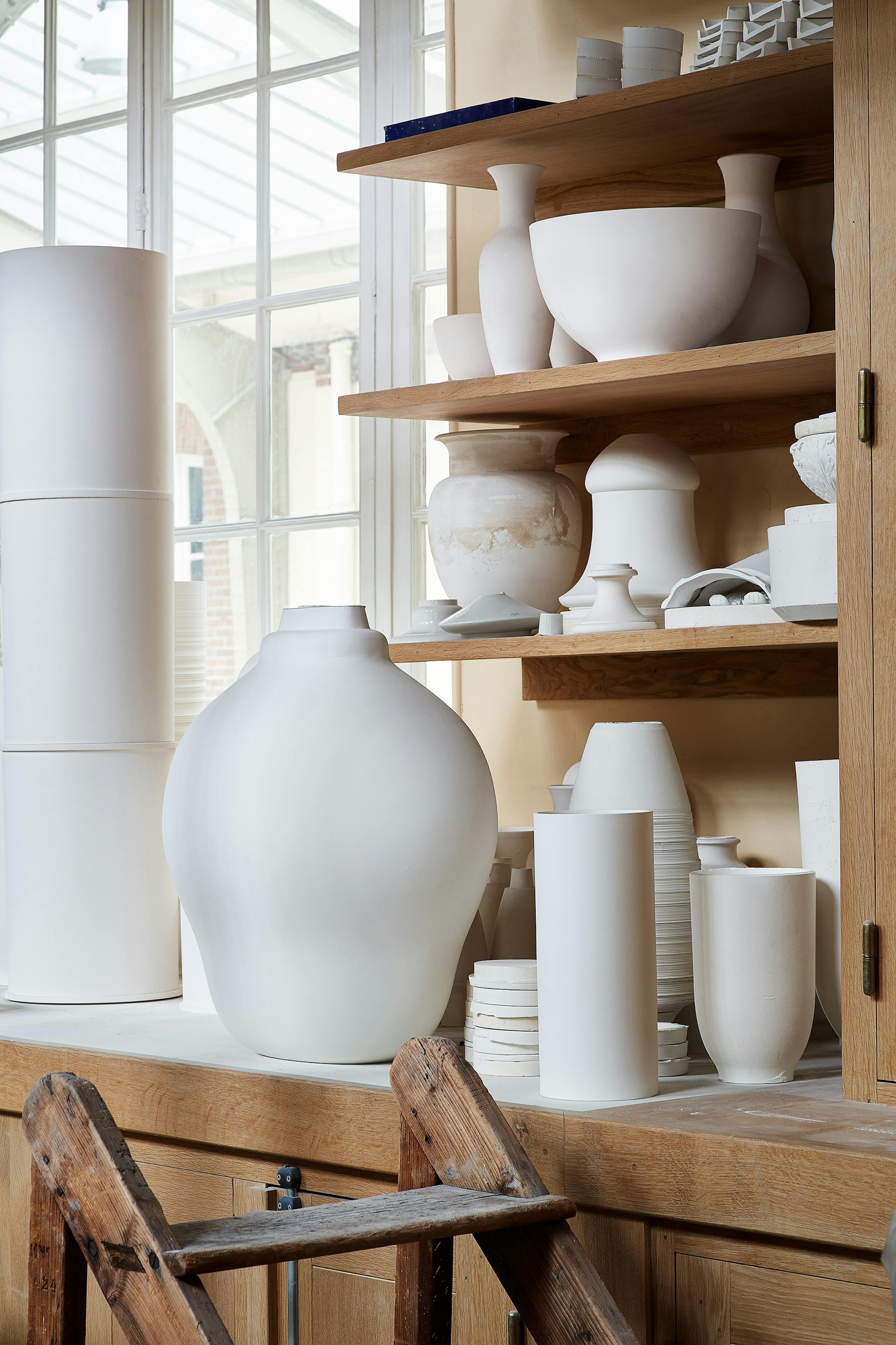 Interior of the Sèvres factory with a collection of various porcelain objects on a wooden shelf