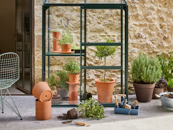 Greenhouse with plant pots and an Eames wire chair
