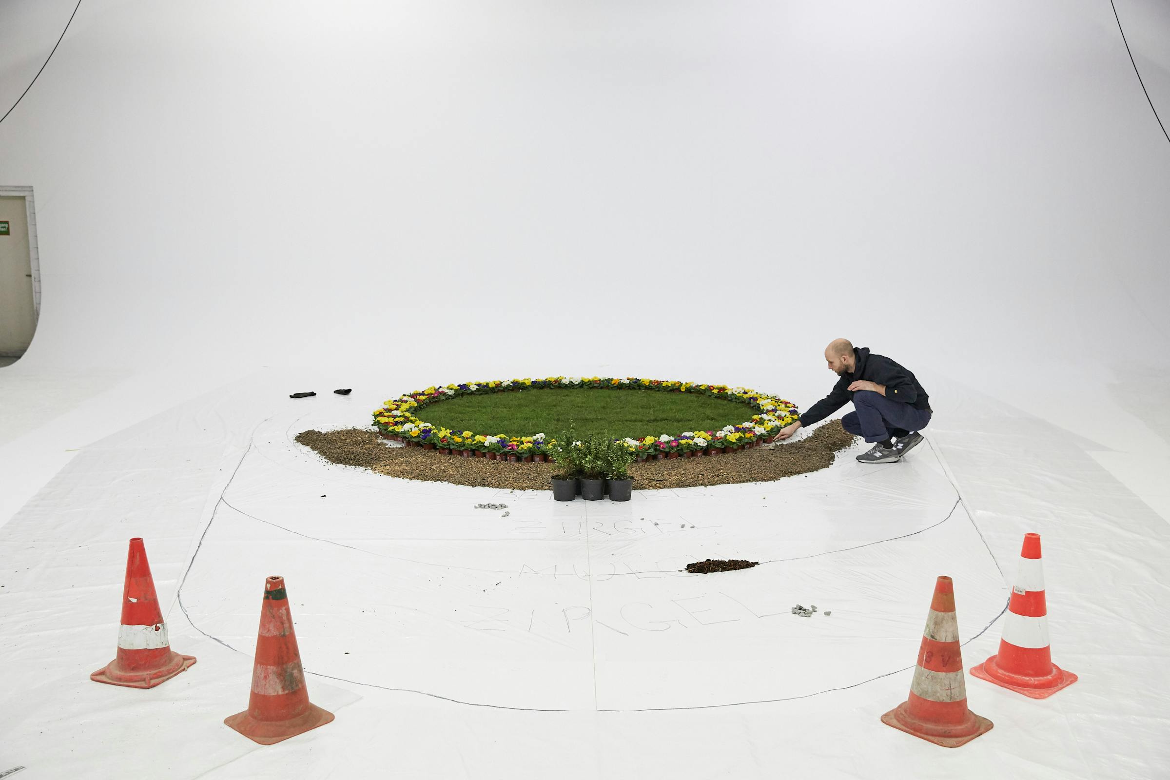 Backstage shot in a large photo studio with a display of flowers and grass