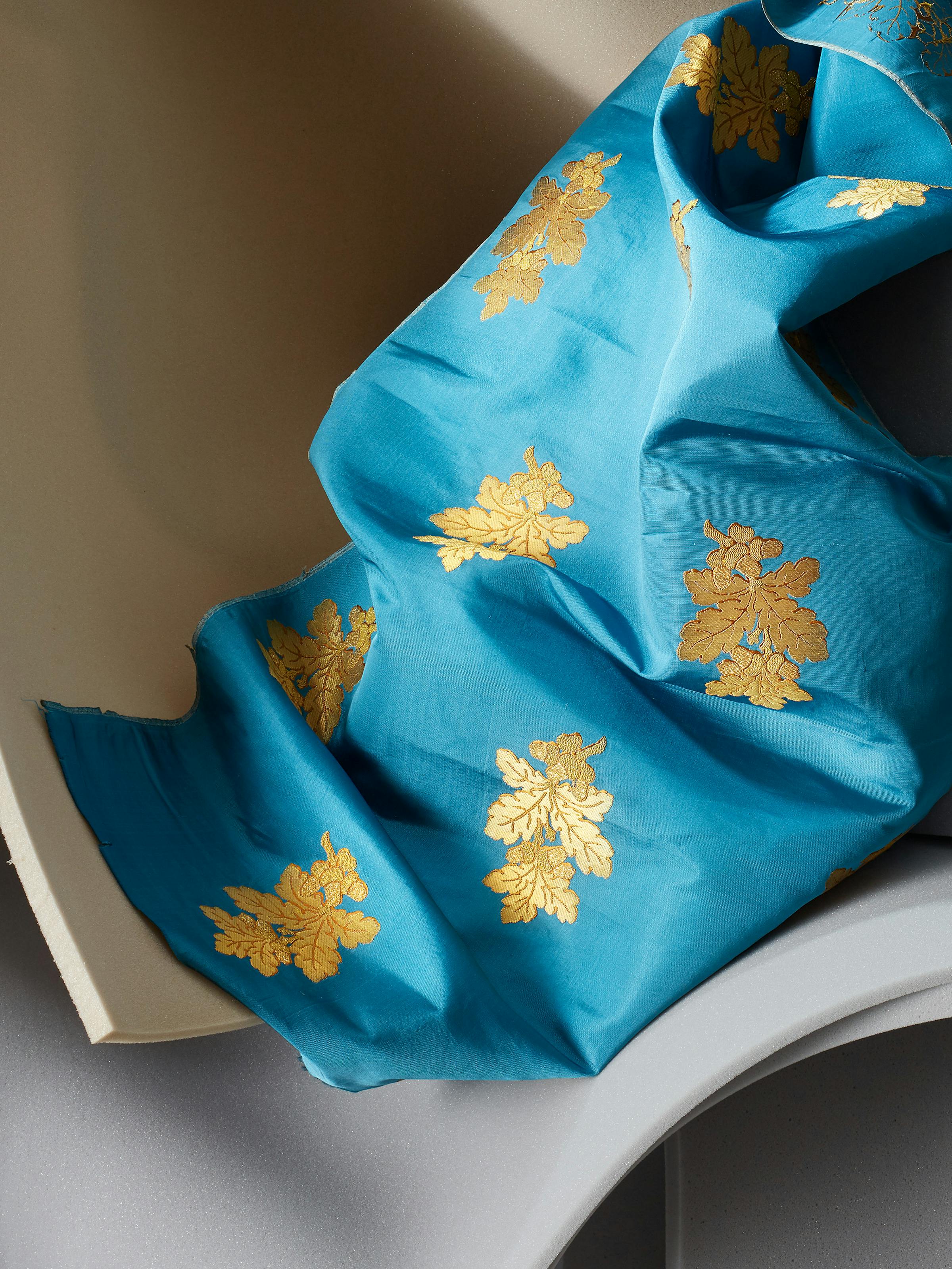 Close-up of a 19th-century fabric in blue and golden colors on grey foam