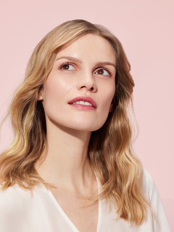 Beauty shot of a blonde woman in front of a light pink background