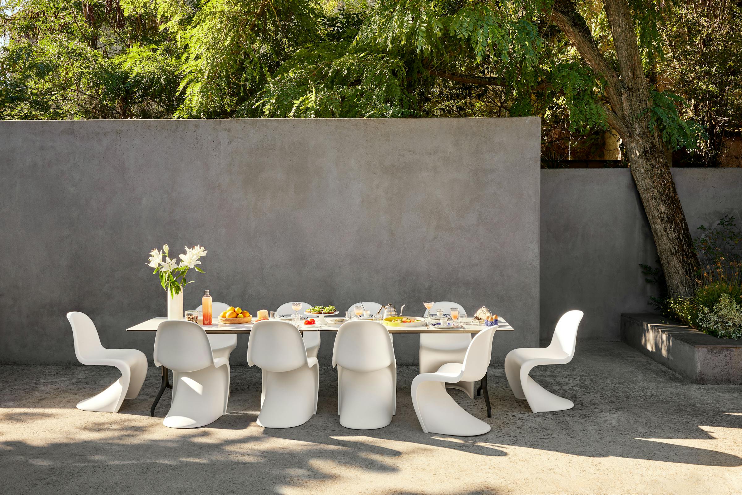 breakfast table on a terrace with white Panton chairs with a selection of food