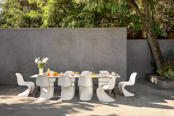 breakfast table on a terrace with white Panton chairs with a selection of food