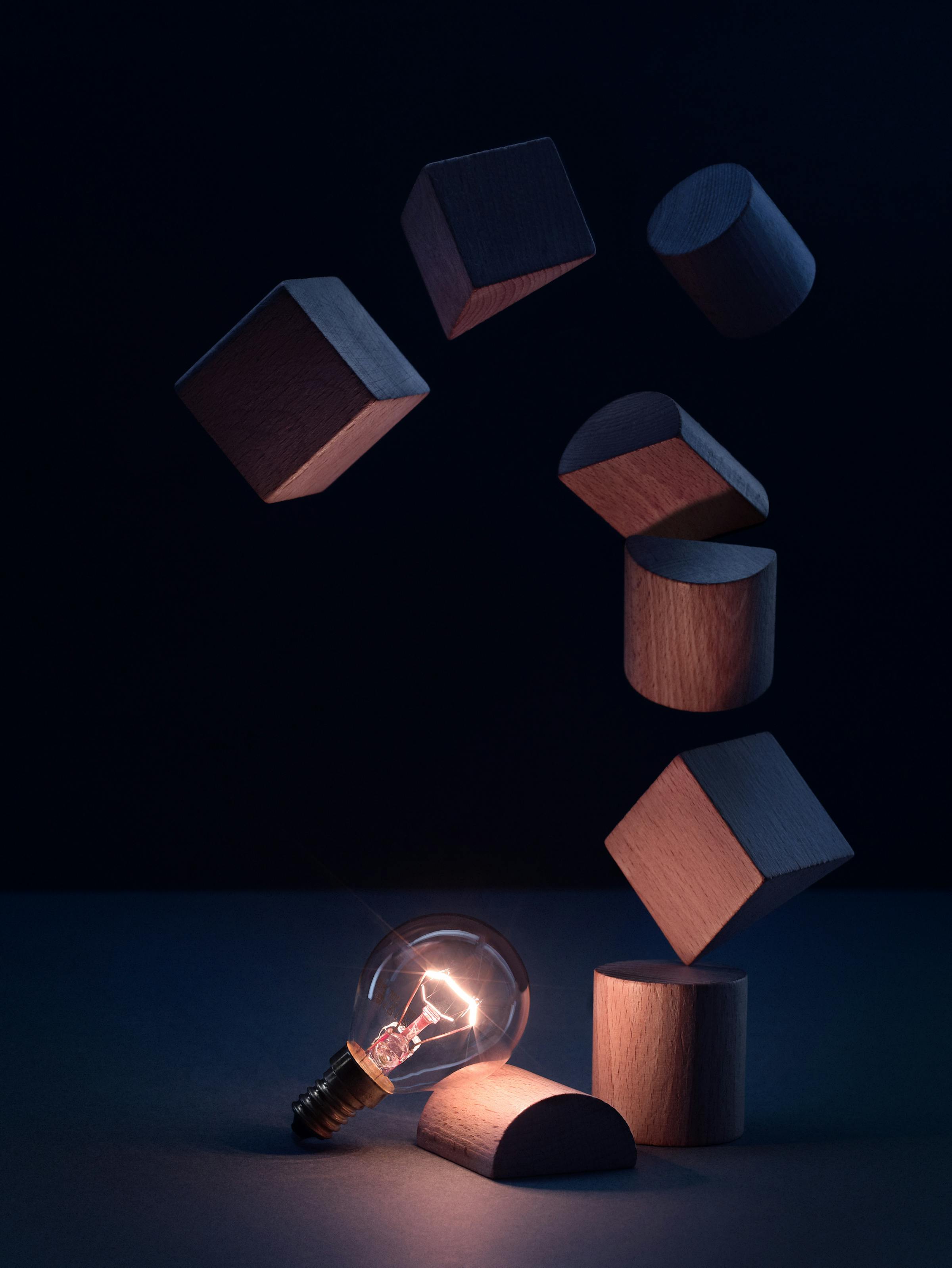Light bulb with wooden building blocks in a dark blue set