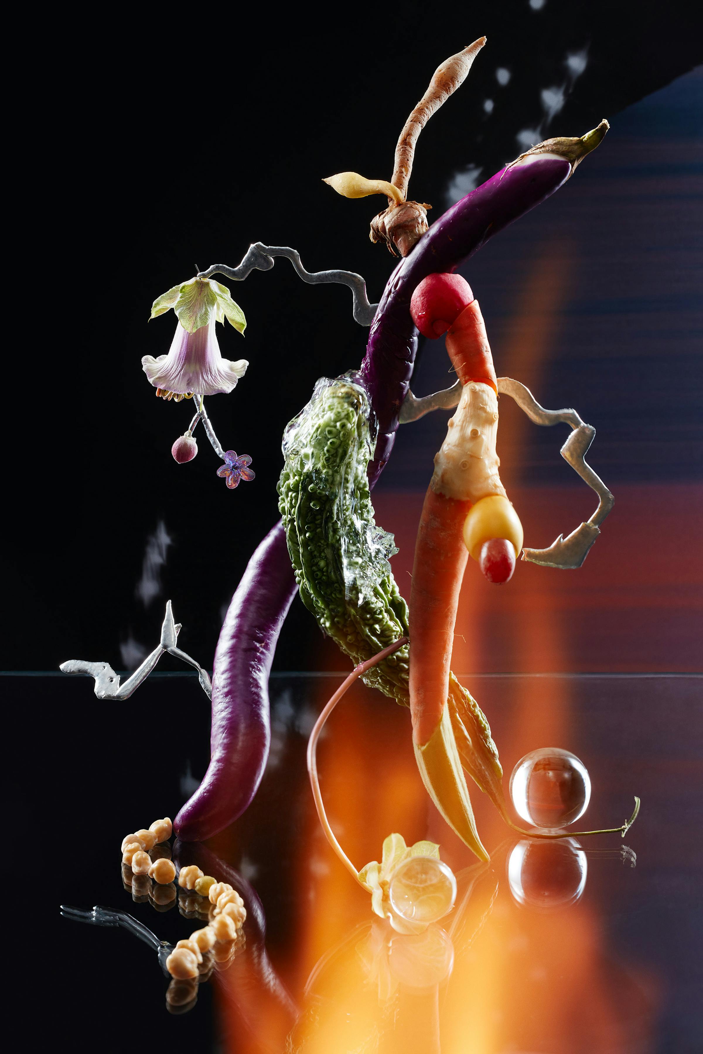 Sculpture made of several vegetables in front of a dark background with fire
