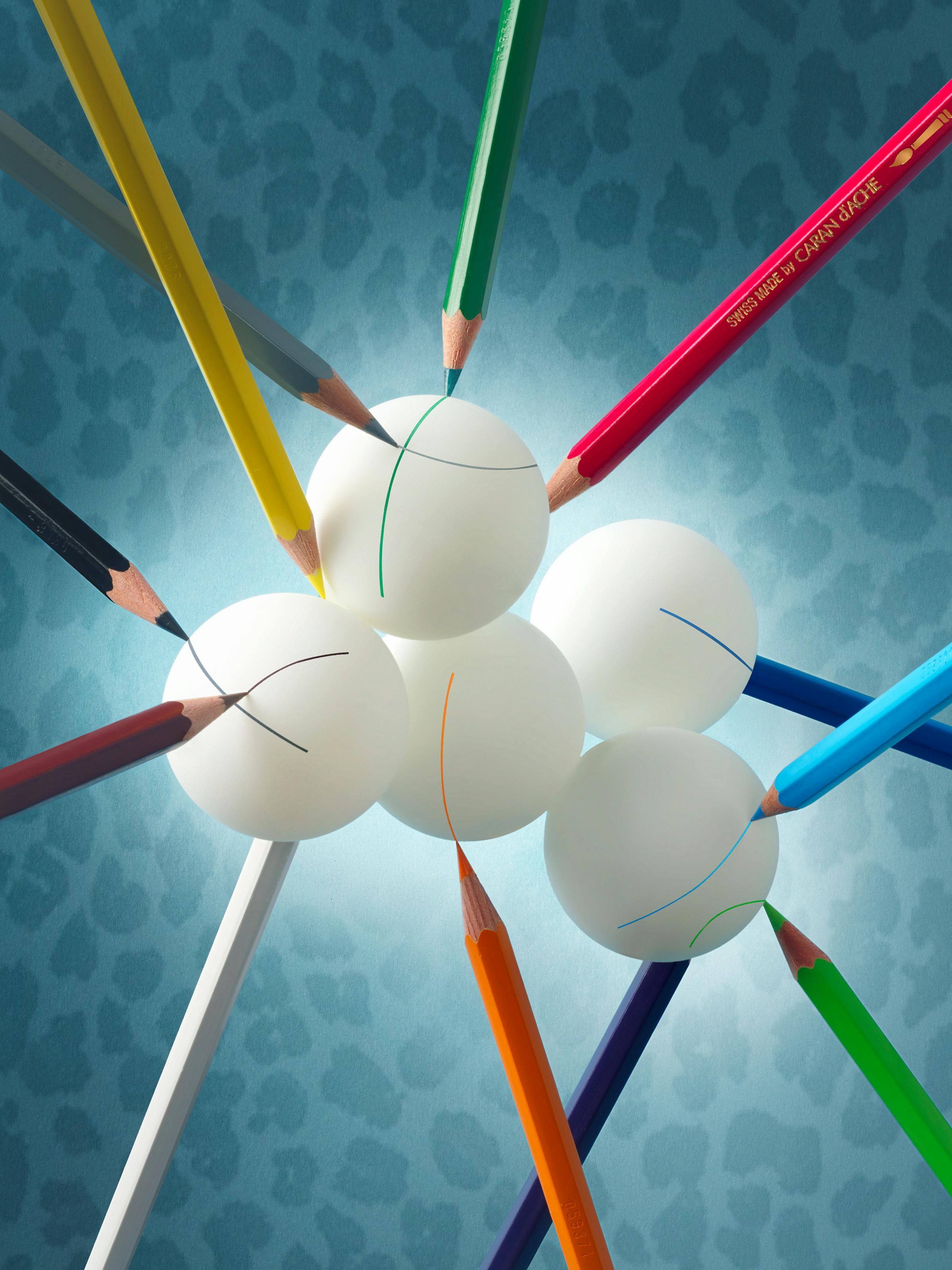 Coloured pencils that balance and mark many ping-pong balls in the shape of clouds