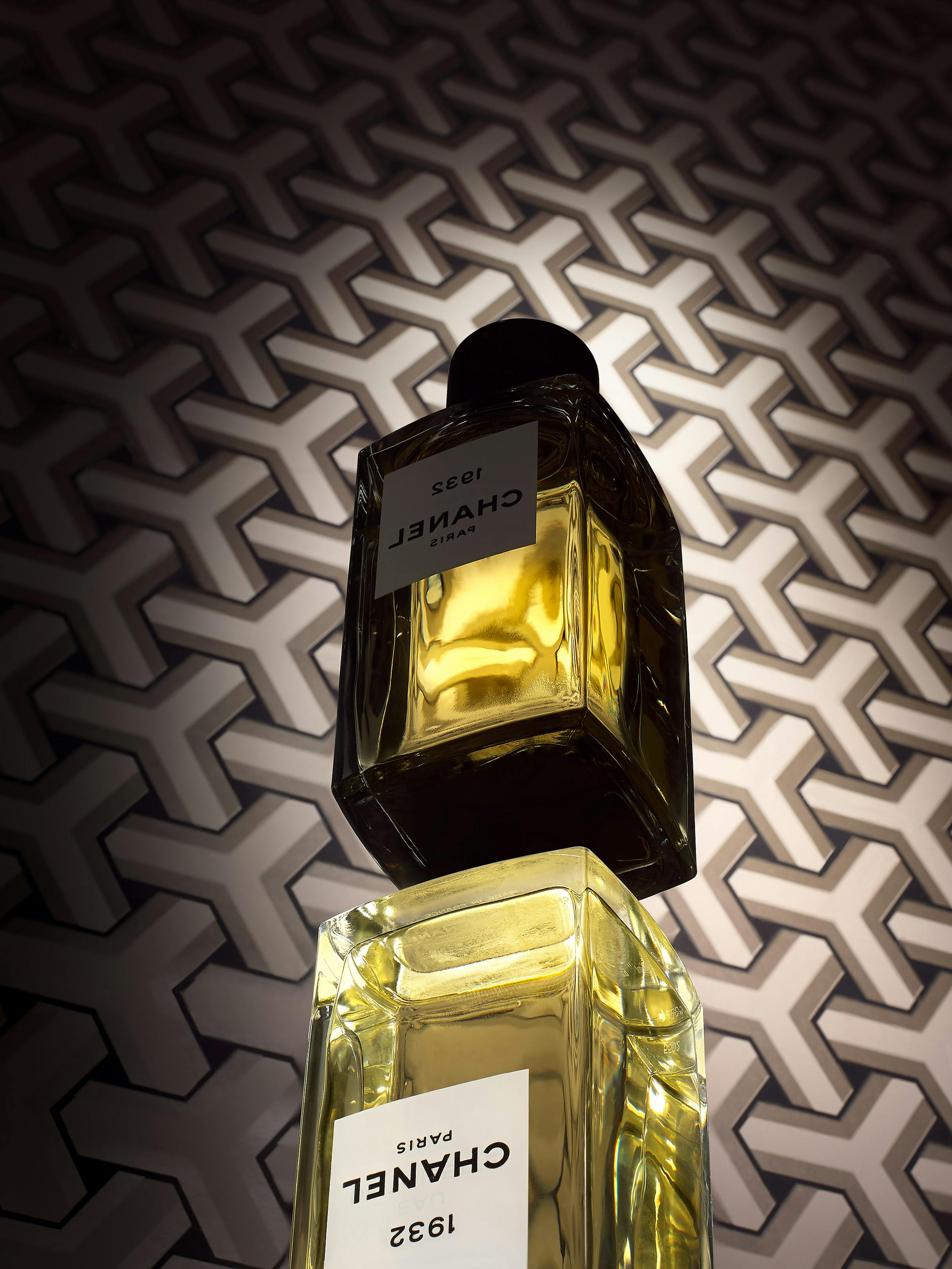 a Chanel perfume on a black background with graphic reflections