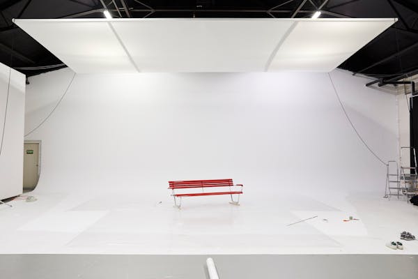 Backstage shot in a large photo studio with a garden bench in a white cove.