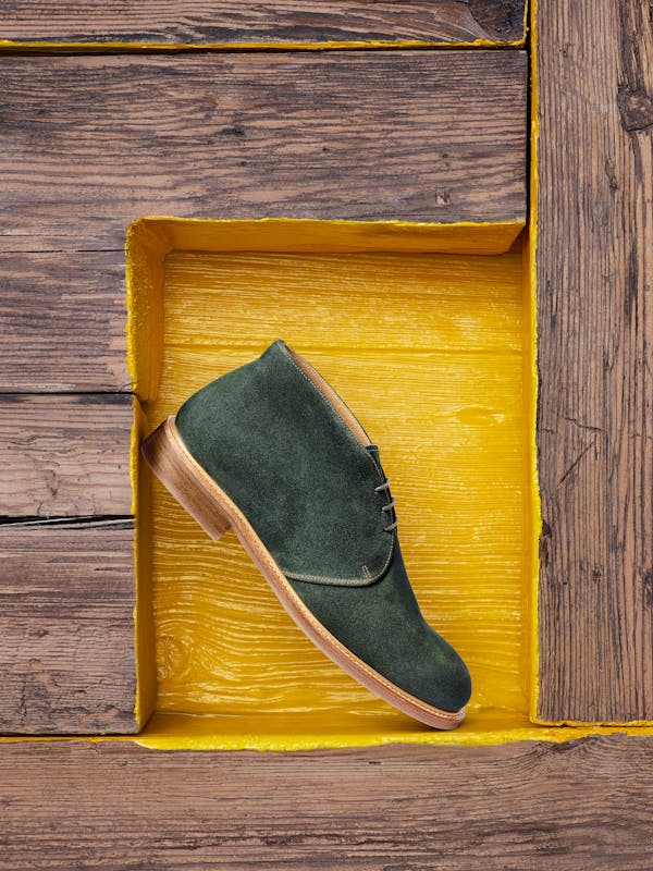 a men's suede shoe in a yellow-painted wooden niche