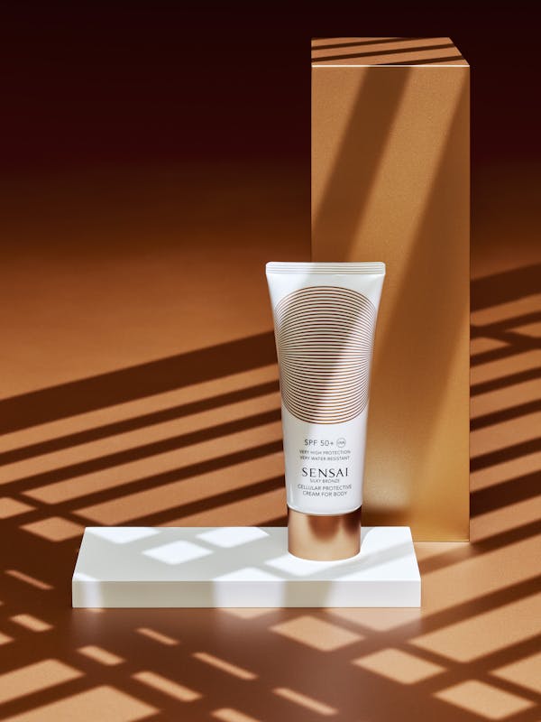 Sunscreen tube on a bronze background with sharp graphic shadows