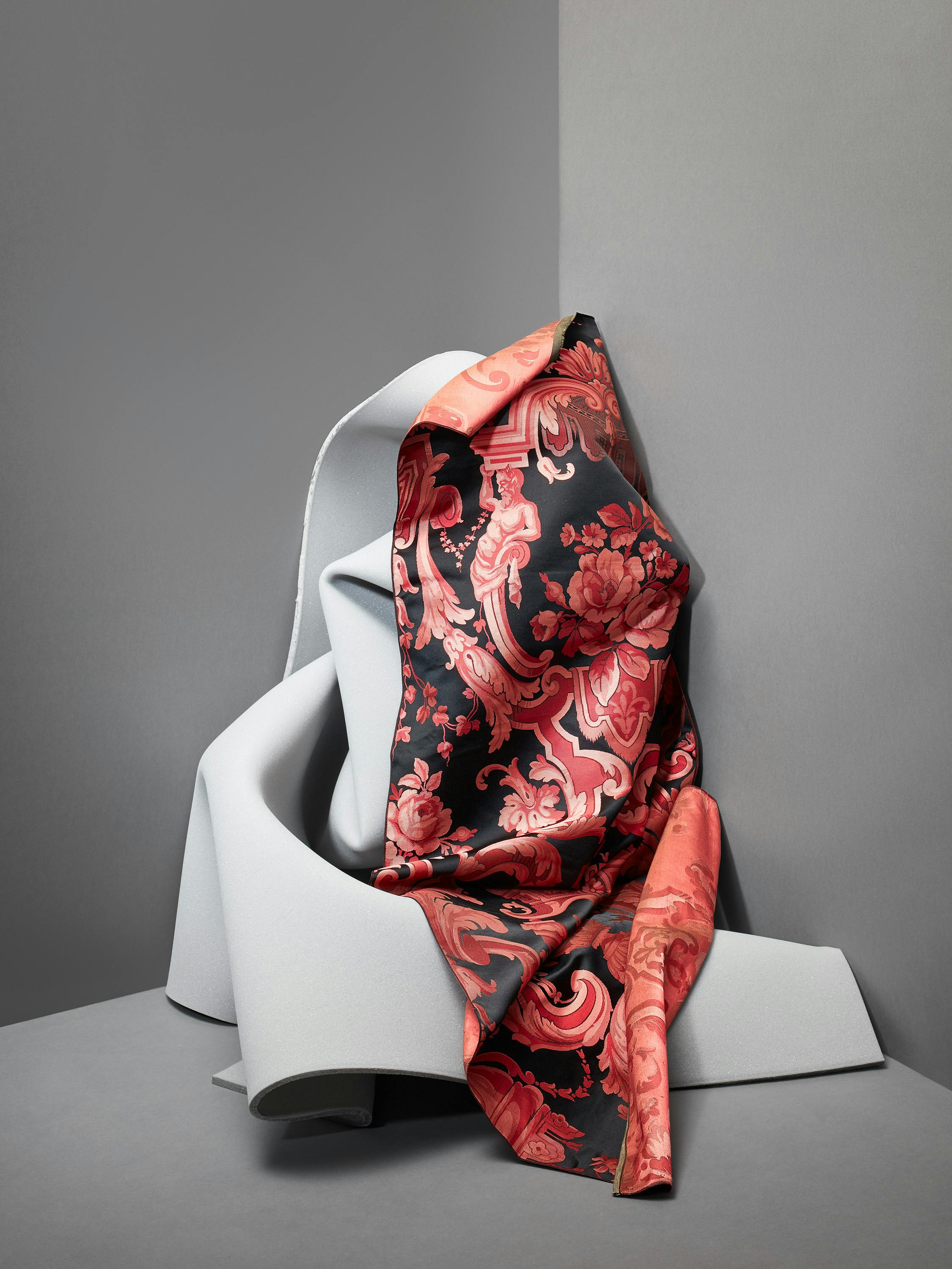 Red fabric with a floral pattern from the 19th century on grey foam in one corn