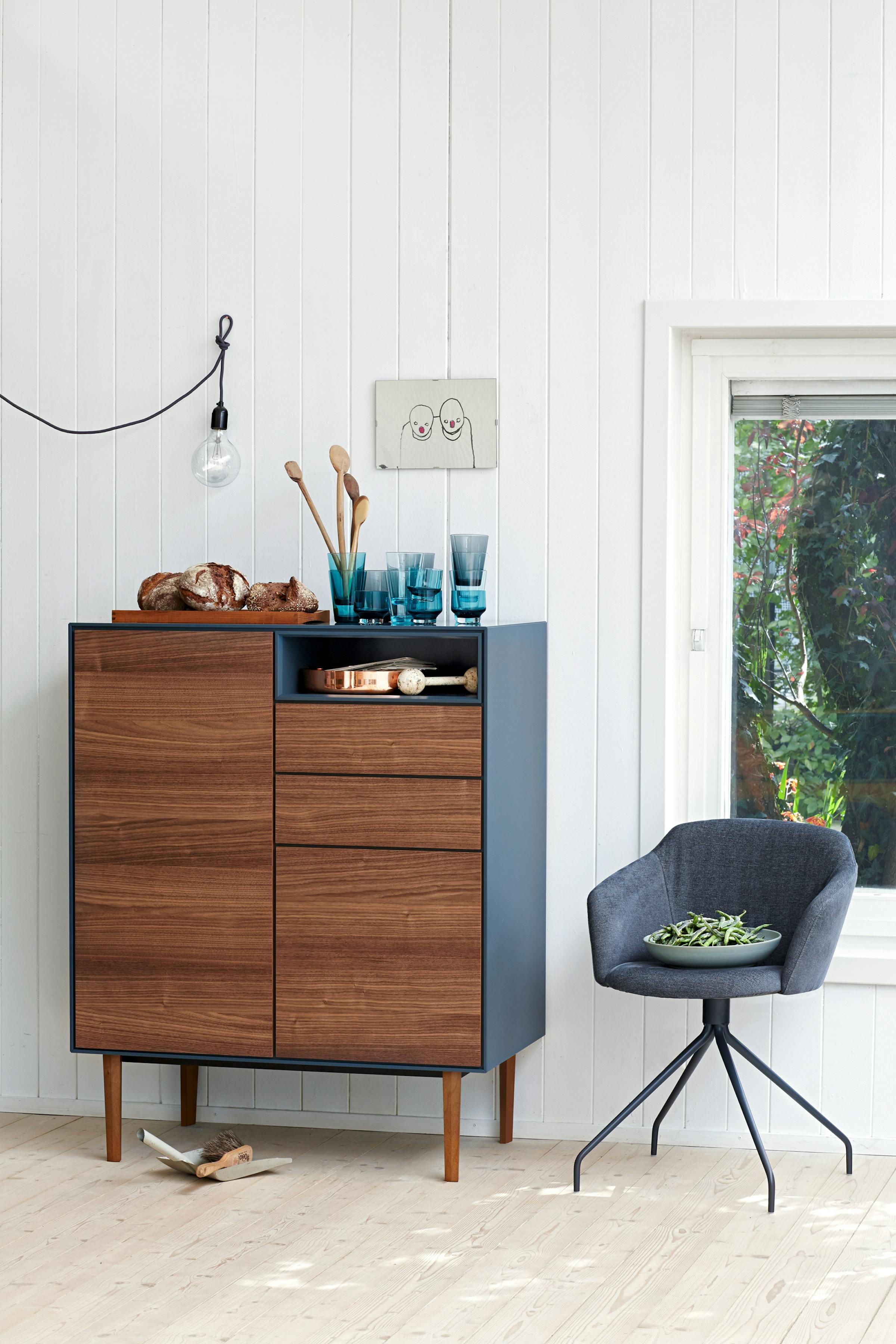 A wooden highboard with a blue side panel and an armchair on the side.