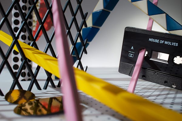 Cassette in an abstract set design with a black plastic grid and colourful rods