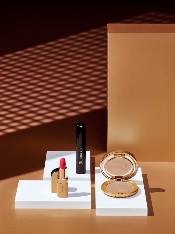 Beauty products on a bronze background with sharp graphic shadows