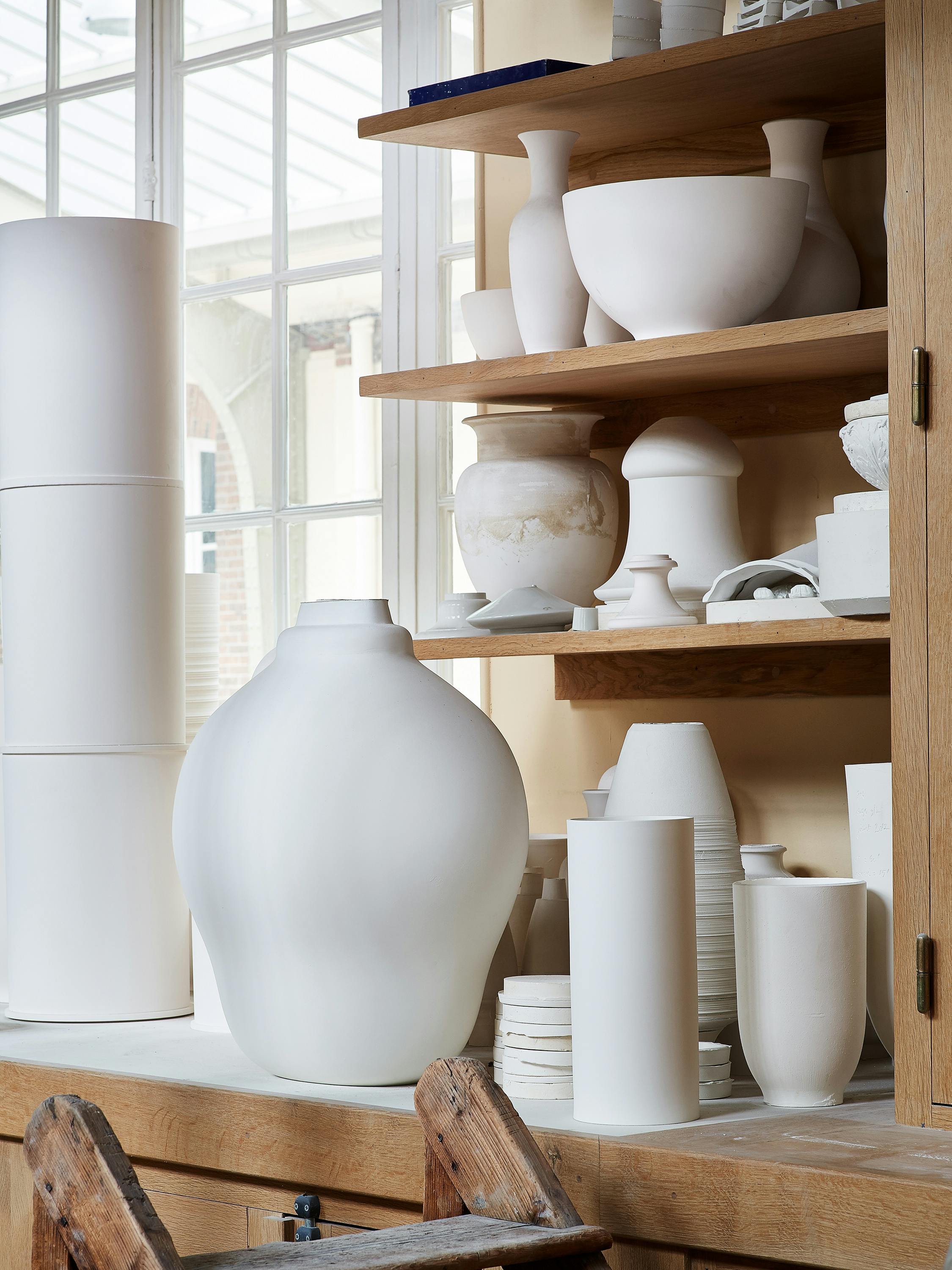 Interior of the Sèvres factory with a collection of various porcelain objects on a wooden shelf