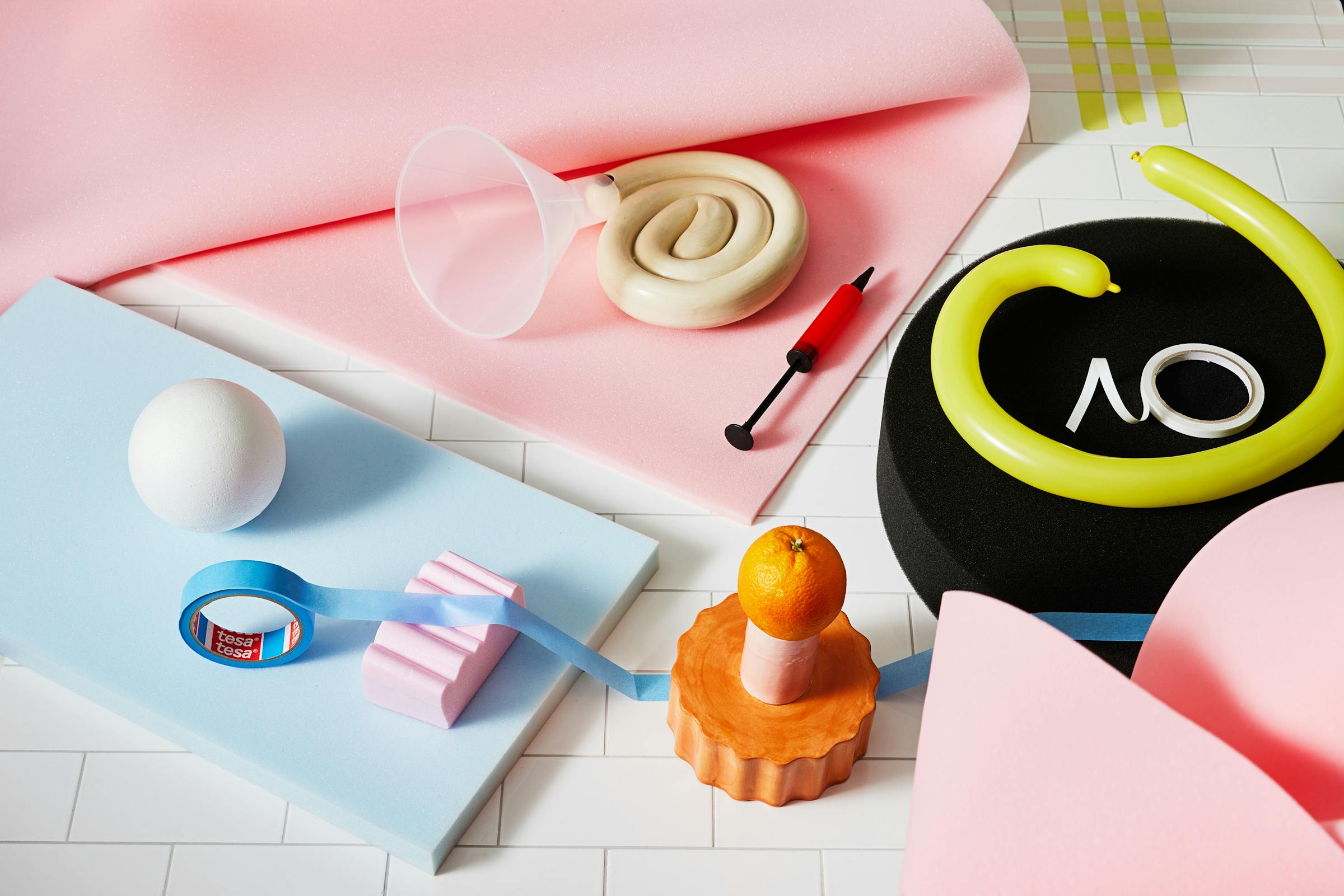 Colourful arrangement of tools and porcelain objects on pink foam