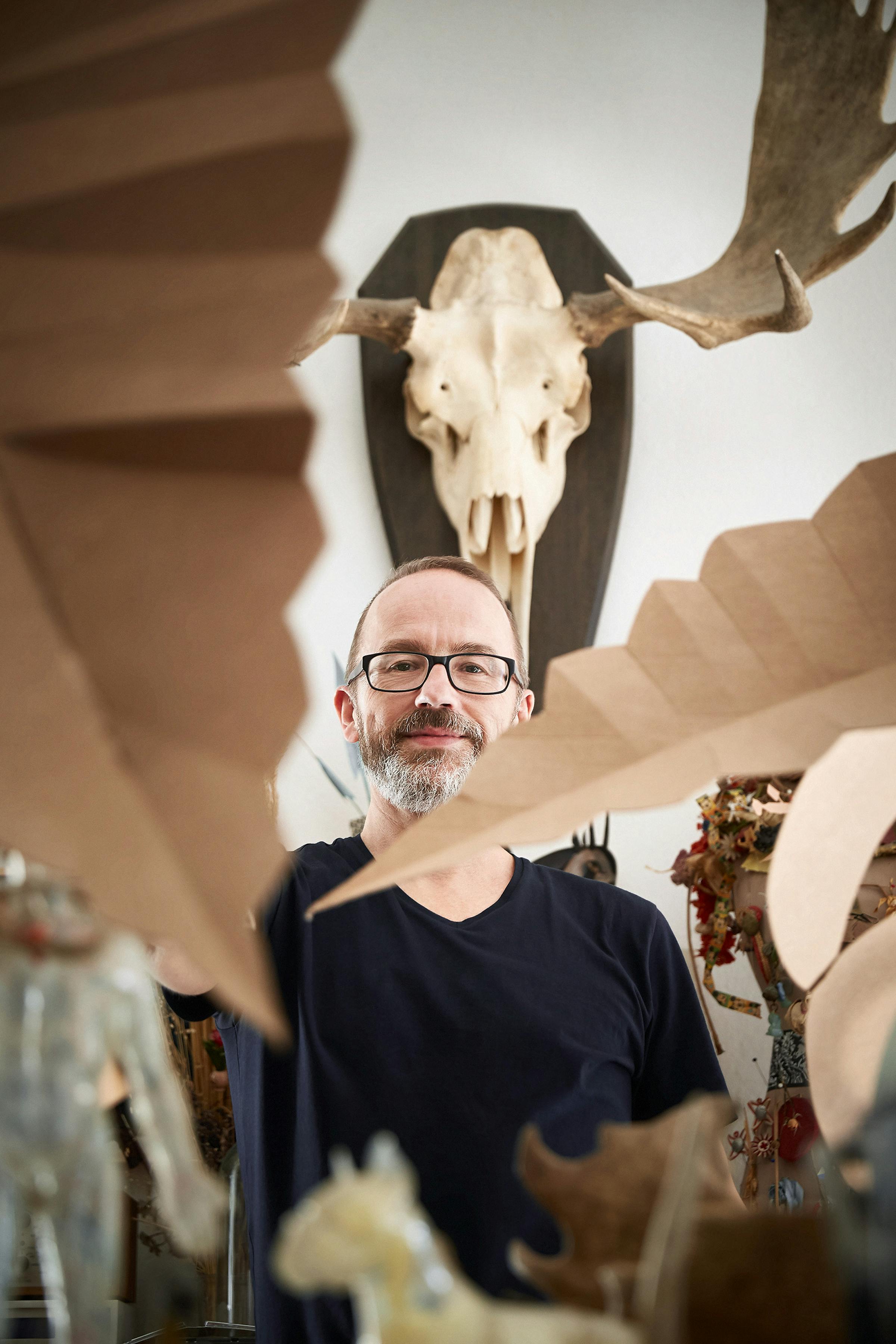 Portrait of the illustrator Daniel Mueller hoding up some cardborad objects