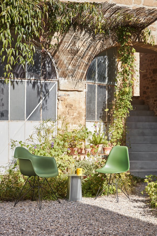 Two green Eames shell chairs in the courtyard of an old building