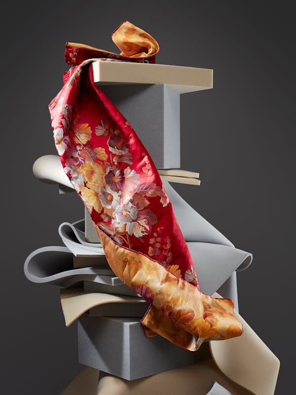 Red fabric from the 19th century with a floral pattern on a tower of grey foam