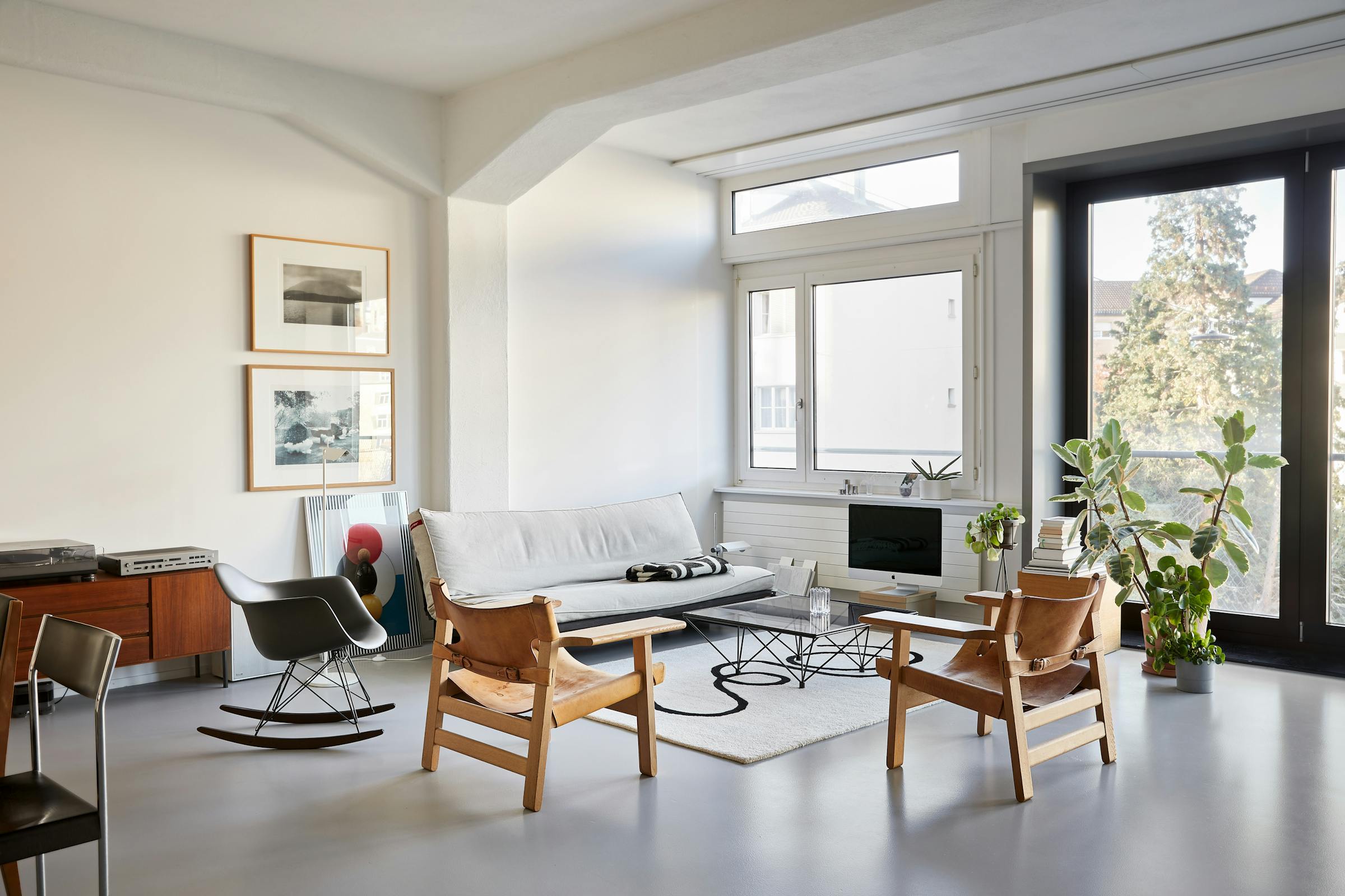 Living room with a light-coloured sofa and two Scandinavian leather armchairs in a loft