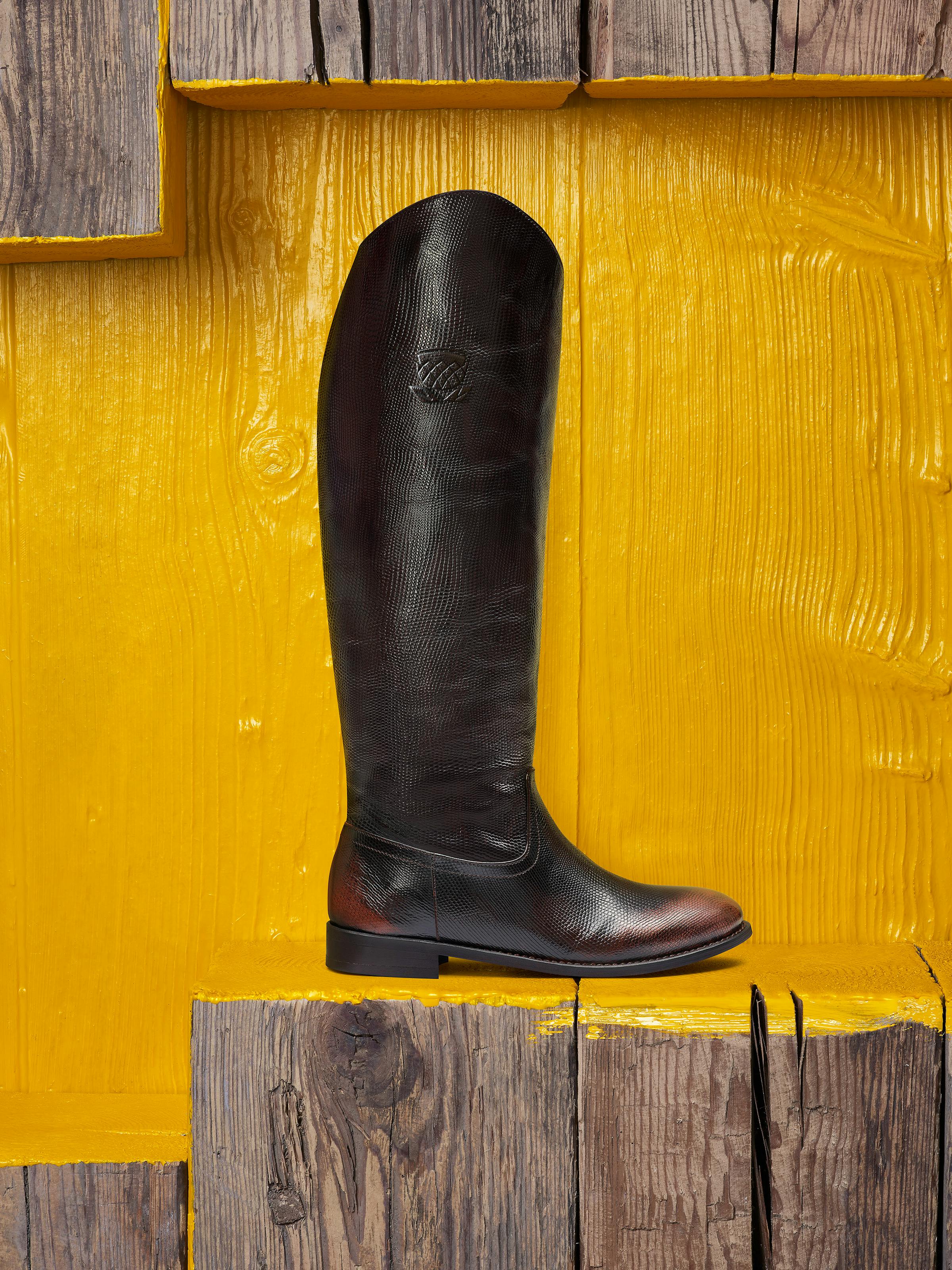 a woman's boot in front of a yellow painted wooden wall