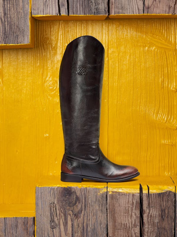 a woman's boot in front of a yellow painted wooden wall