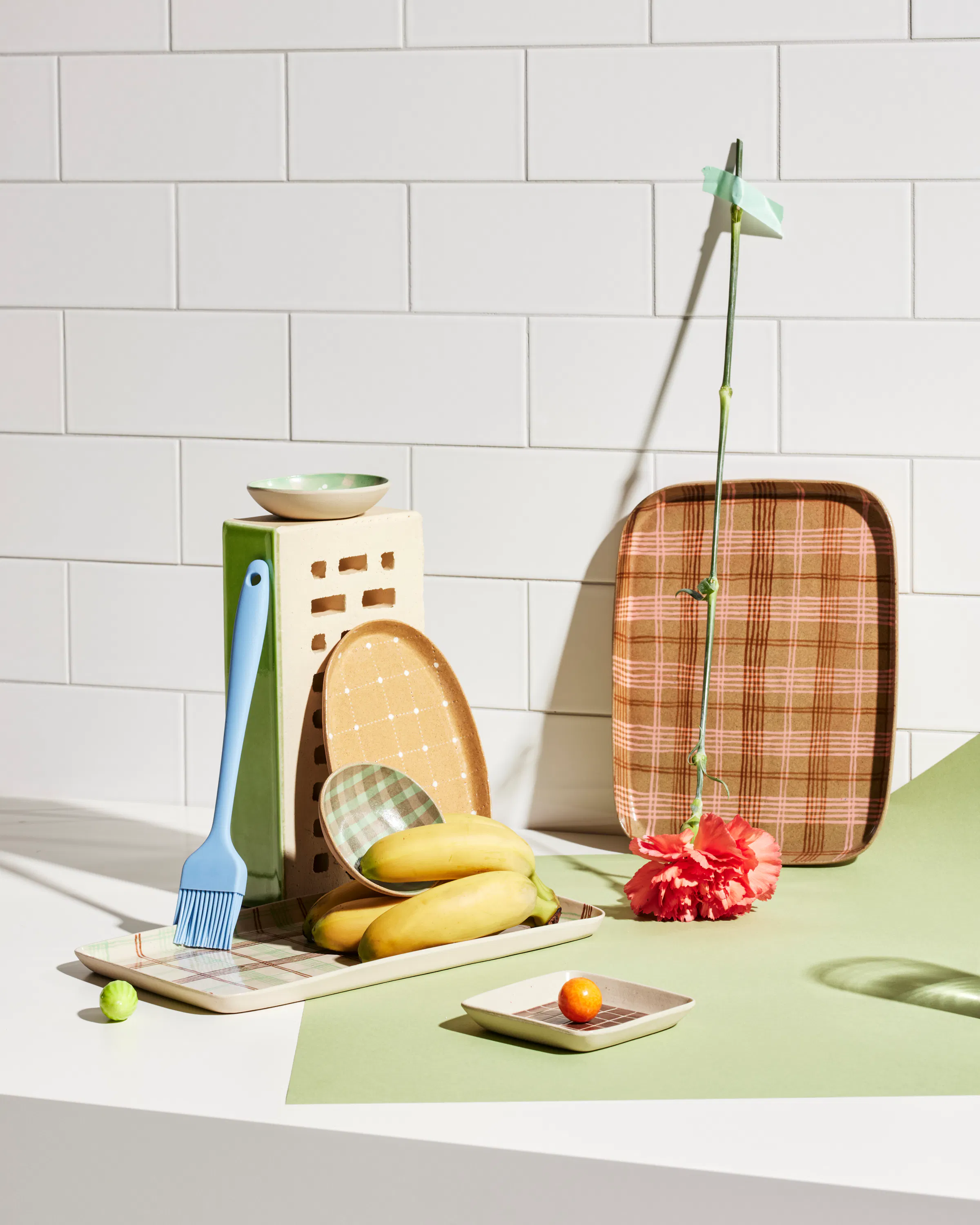 Various ceramic objects by Simone Fennel in front of a wall with tiles and a green paper